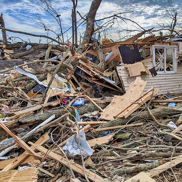 The aftermath of a destructive tornado- an entire building pulled apart, with wood and other debris scattered everywhere, from FurHaven Pet Products