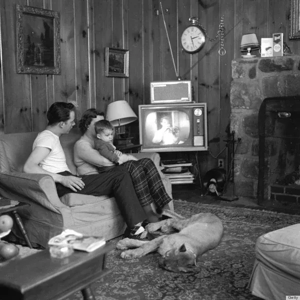 A family sits and watches TV with a Puma at their feet, from FurHaven Pet Products