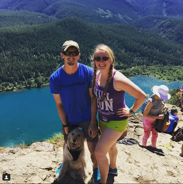 A picture of two humans and their golden dog standing on a rocky outcropping at Rattlesnake Ledge, from FurHaven Pet Products